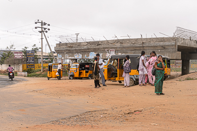 Des passagères attendent près d'une file de rickshaws sous un viaduc en construction à Coimbatore.
