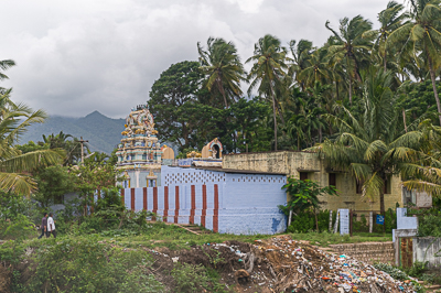 Un petit temple hindou apparaît parmi les cocotiers, devant les contreforts des Ghâts.