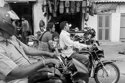 Une famille de trois personnes avance à moto dans la circulation.
