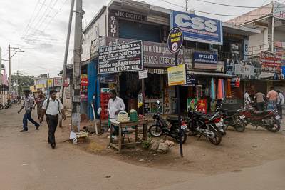 Un vendeur de fleurs occupe un carrefour encombré de commerces et de motos à Kuniamuthur.