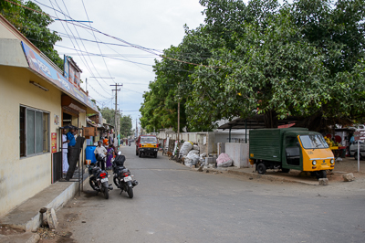 À l'entrée d'une rue plus calme, motos et petits véhicules stationnent sous les arbres.