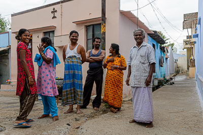 Six habitants posent en souriant devant un petit bâtiment surmonté d'une croix.