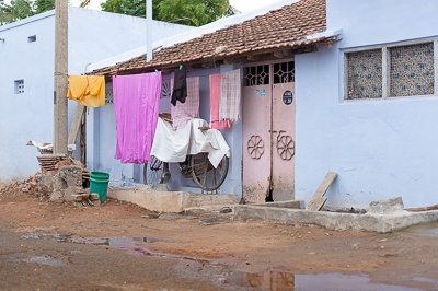 Draps et vêtements vivement colorés recouvrent presque entièrement la façade d'une petite maison.