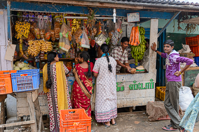 Bananes, légumes et marchandises débordent de la petite épicerie où les clients se pressent au comptoir.