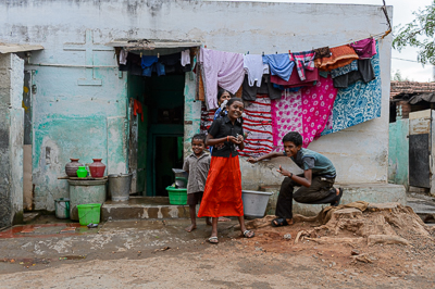 Un garçon et une jeune fille posent devant une maison dont la façade disparaît derrière le linge.