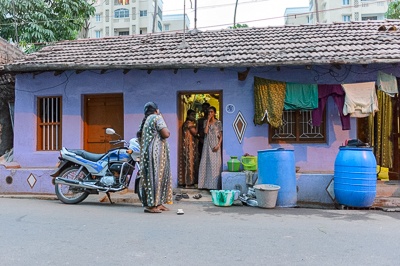 Devant la maison violette, plusieurs femmes discutent parmi les bassines et les grands bidons d'eau bleus.