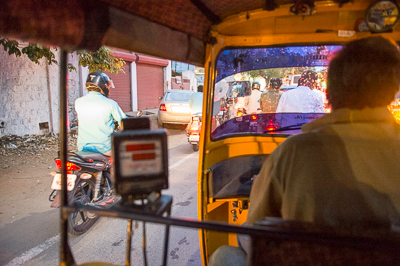 Depuis le rickshaw, la circulation du soir apparaît à travers le pare-brise mouillé et les feux rouges.
