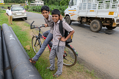 Deux écoliers sourient près de leurs bicyclettes au bord de la route.