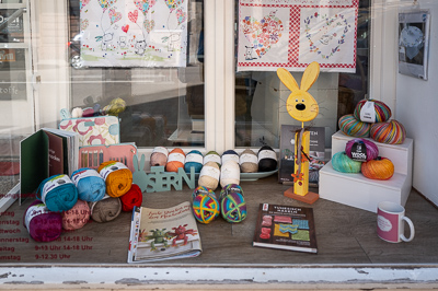 Un lapin jaune souriant monte la garde au milieu des pelotes multicolores, des catalogues de tricot et des ouvrages de crochet. Les couleurs éclatent derrière la vitre, saturées comme pour défier l’usure du temps. Cette vitrine de Stuttgart n’est pas seulement un magasin, c’est une petite scène joyeuse, bricolée avec tendresse, qui invite à ralentir.