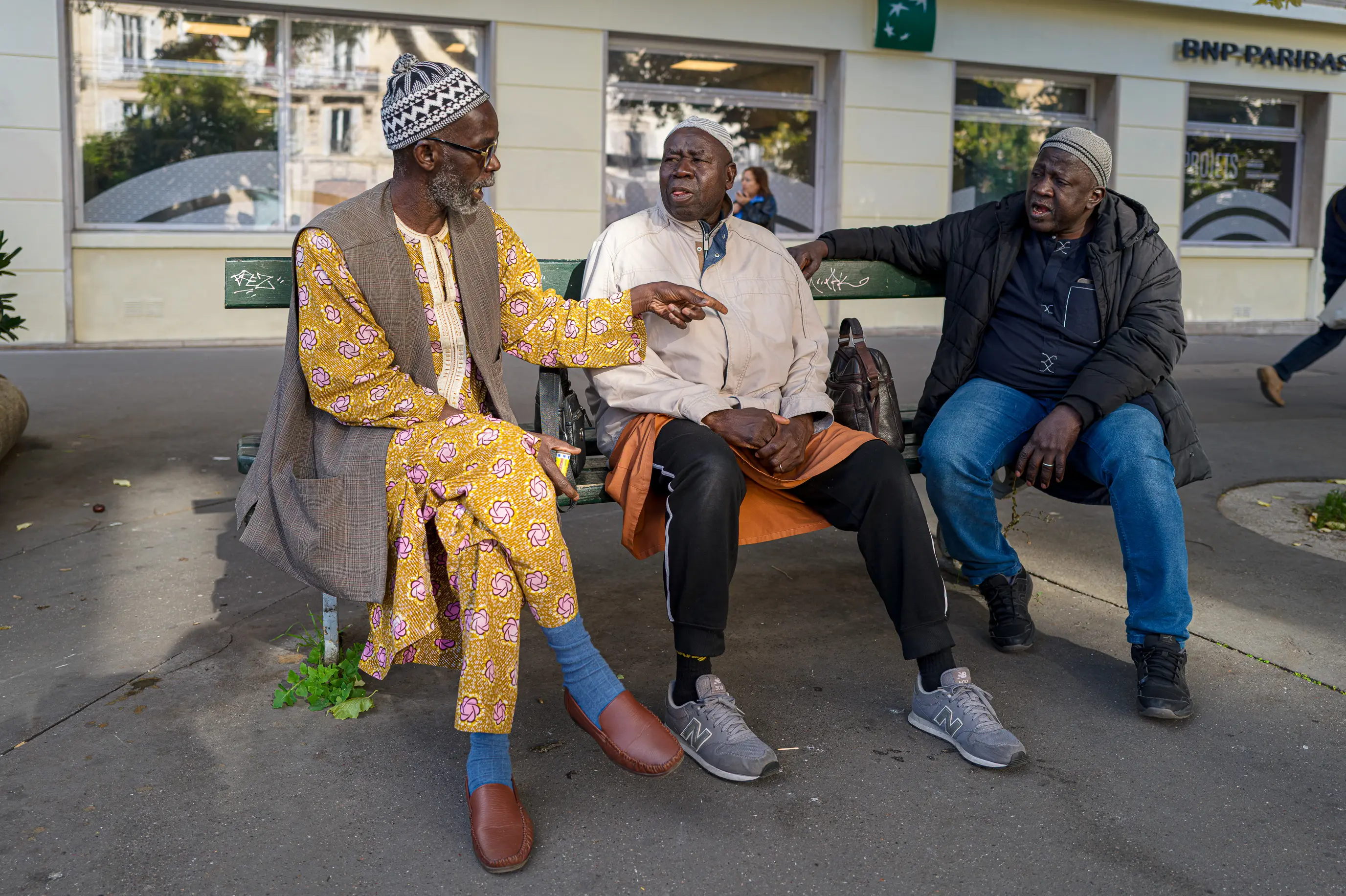 Conversation animée entre trois hommes assis sur un banc