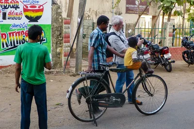Je montre la photographie sur l’écran de mon appareil à un homme près de son vélo, sur lequel un enfant en jaune est assis ; un garçon en vert se tient à gauche.