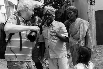En noir et blanc, je montre la photographie sur l’écran de mon appareil à deux hommes, près d’une femme en sari et d’une petite fille.