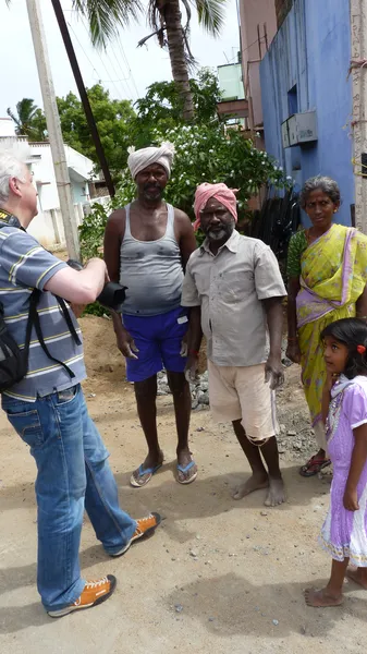 Appareil abaissé, je fais face à deux hommes, une femme en sari jaune et une fillette, dans une ruelle bordée de maisons.