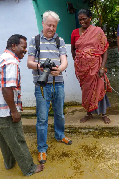 Je regarde la photographie sur l’écran de mon appareil avec un homme souriant et une femme en sari rose, devant une maison.